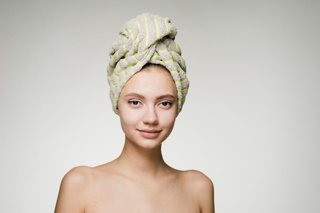 attractive young girl with clean skin, on her head a green towel, day spaの写真素材