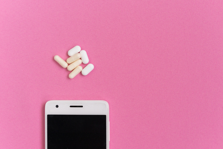 on a pink surface is a white smartphone and tablets