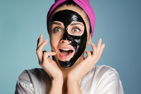 girl with a pink towel on her head applied a cleansing mask on her faceの写真素材