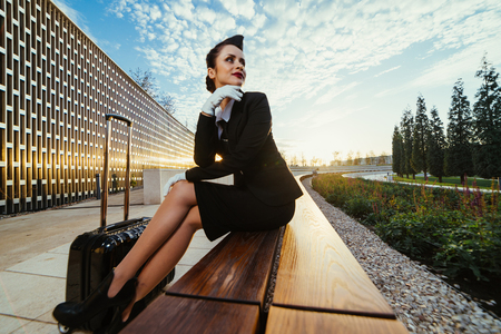 girl stewardess with a suitcase on a cloudy sky backgroundの写真素材