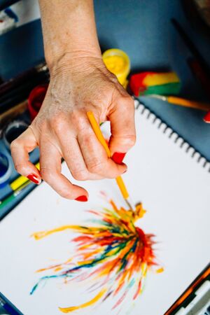 on the artist draws on a white paper with a brush and watercolorsの写真素材