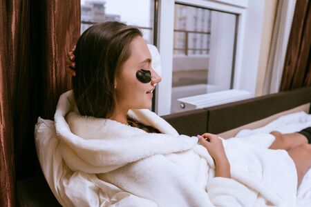 young cute girl in a white terry dressing gown woke up early, under the eyes of black patchesの写真素材