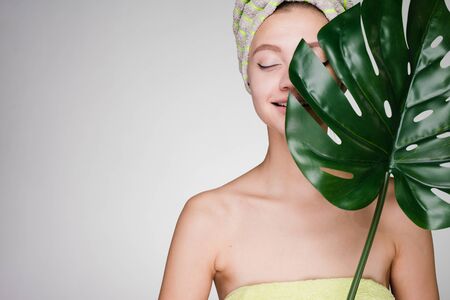cute young smiling girl with a towel on her head holding a green leafの写真素材