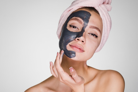An attractive beautiful girl with a pink towel on her head applied a clay maskの写真素材