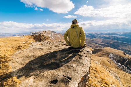 single man traveler sits on the edge of a cliff and enjoys natureの写真素材