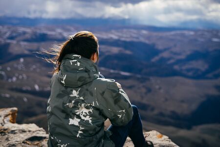 girl tourist sits and looks at the mountainsの写真素材