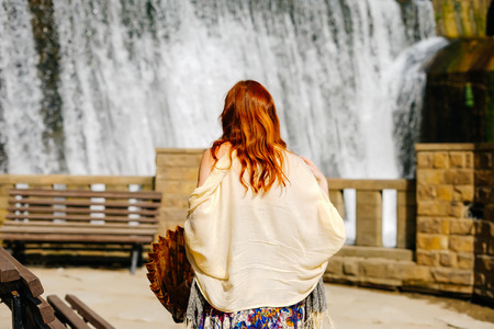 a woman with red hair standing on a waterfall backgroundの写真素材