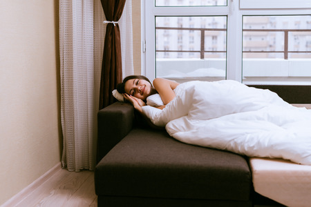 a young girl lies on the couch under a blanket trying to sleep