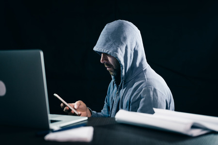 mysterious bearded man hacks the password on the phone in the darkの写真素材