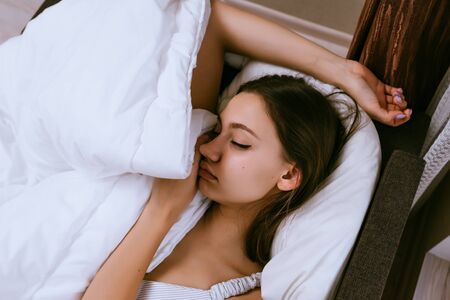 young girl lies in bed, asleep, does not want to get up
