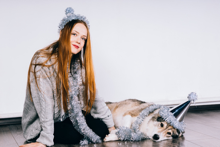 happy cute red-haired girl sitting on the floor with her dog, waiting for the new year 2018 and christmasの写真素材
