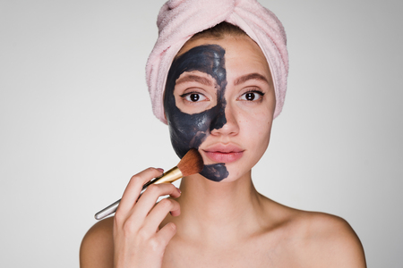 woman with a towel on her head apply a cleansing black mask on her faceの写真素材