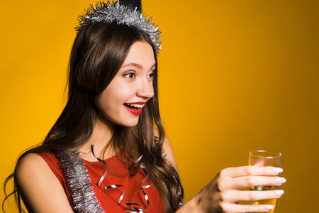 happy drunk girl with a festive hat on her head holding a glass of champagne in her handの写真素材