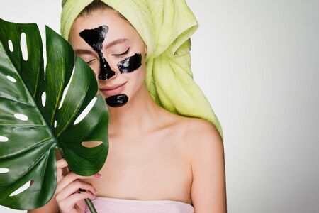 A woman in a towel on her head applied a mask to problem areas of the faceの写真素材