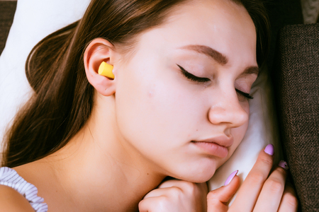 woman sleeping in bed with earplugs in her earsの写真素材
