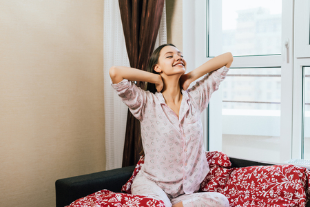 happy woman sitting on a bed in pajamasの写真素材