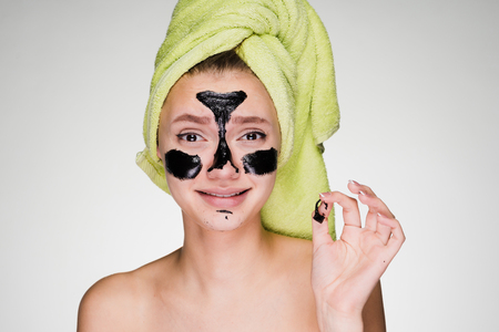 a frightened woman with a towel on her head removes the mask from her faceの写真素材