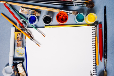 on a blue table are art supplies, white paper and many brushesの写真素材