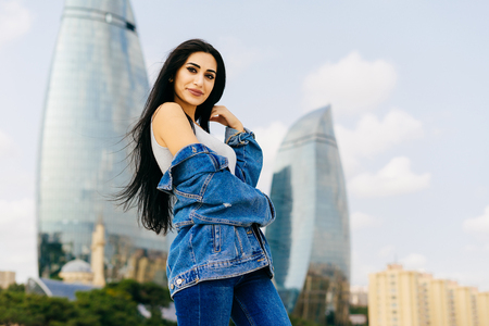 attractive black-haired girl is traveling, posing against the background of modern architecture of Baku cityの写真素材