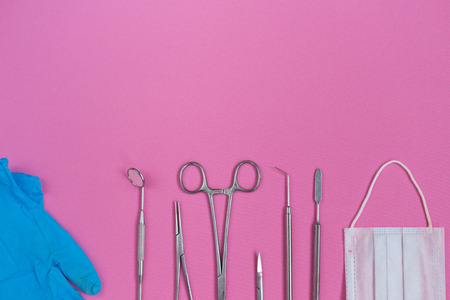 on a pink background lie dental medical instruments and glovesの写真素材