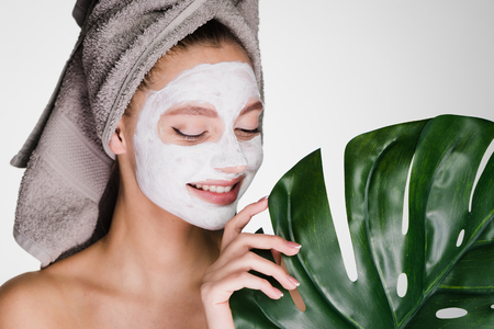 happy woman with a towel on her head applied a mask to her faceの写真素材