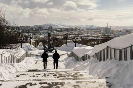 people go down the snow-covered stairs against the backdrop of the cityの写真素材