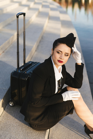 woman stewardess in uniform sits on the stepsの写真素材