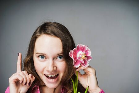 funny young girl in pink shirt is happy holding a pink flowerの写真素材