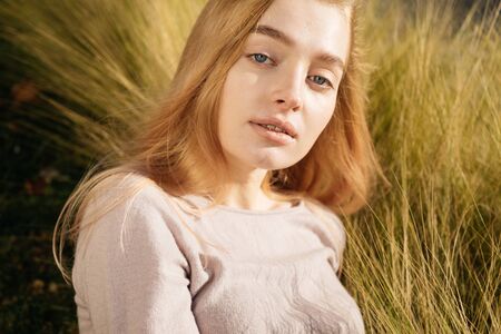 cute young blond model girl lies in the field and posing in the sun
