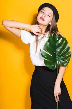 attractive young girl model in fashionable clothes posing with green leafの写真素材