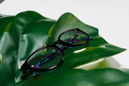 on a white background, on a green sheet lie glasses in black rimの写真素材