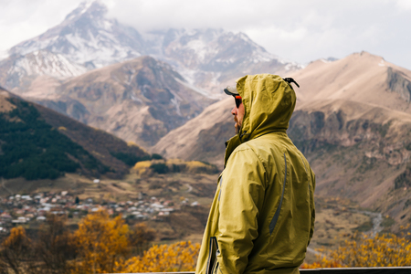 male traveler in a warm jacket travels through the mountains, enjoys nature