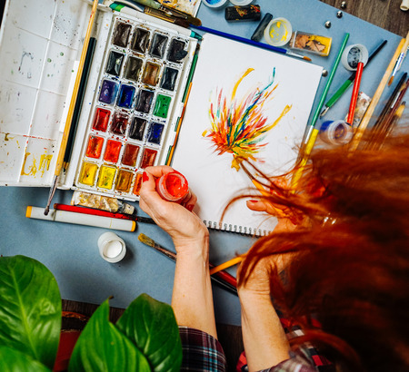 woman painter paints watercolor on white sheet of paperの写真素材