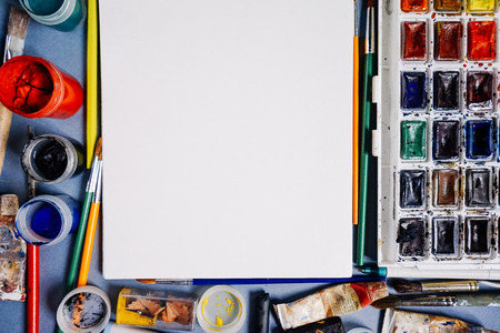 a sheet of white paper stands against a background of multicolored paintsの写真素材