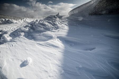 snowy field against a blue sky on a sunny dayの写真素材