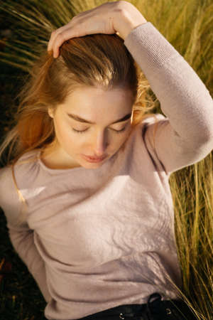 cute young blond girl enjoying the sun and warmth outdoors, eyes closedの写真素材
