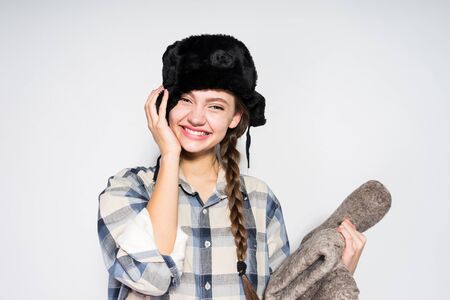 happy laughing Russian girl in black fur hat holds winter boots in handsの写真素材
