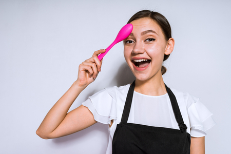 happy young girl cook holding a pink spoonの写真素材
