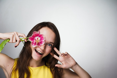 happy laughing young girl holding a pink flower, celebrating Mother's Dayの写真素材