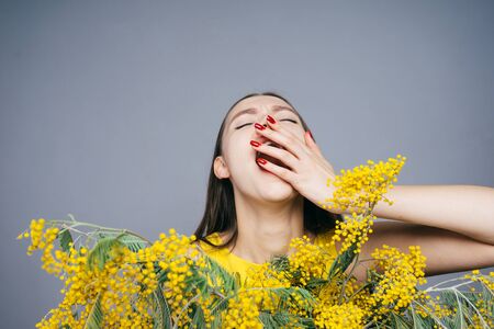 woman among the little yellow flowers yawns, March 8, women's dayの写真素材