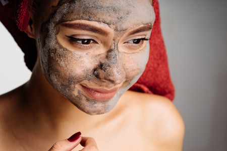 the amazed woman after the shower puts on her face a cleansing maskの写真素材