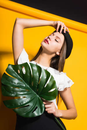 woman in a hat with a green leaf posing on the cameraの写真素材