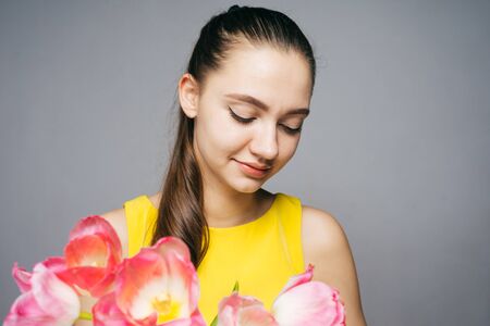 the amazed woman holding a bouquet of flowers, tulips, on March 8, mother's dayの写真素材