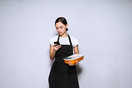 woman in kitchen apron looks at phoneの写真素材