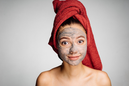 lovely beautiful girl with a red towel on her head has put a useful mask on her faceの写真素材