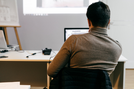young male designer office worker working on project on laptopの写真素材