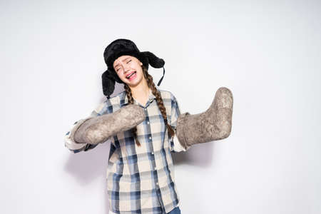 funny young russian girl in a warm fur hat holds gray felt bootsの写真素材