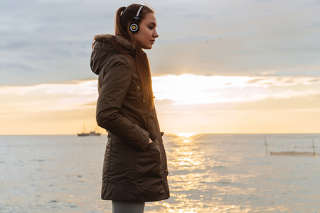 motivated young girl stands by the sea in headphones, street training and motivationの写真素材