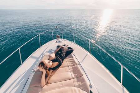 a slender young girl lies on her white yacht, travels the Caribbean sea, relaxesの写真素材