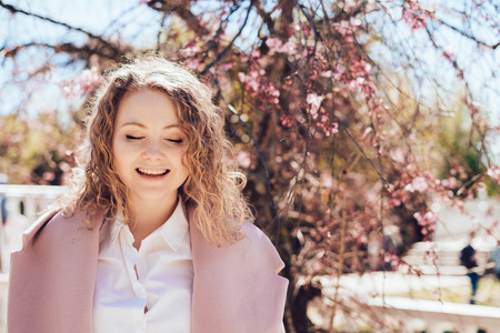 beautiful happy young woman is walking through the park on a warm spring day, laughing